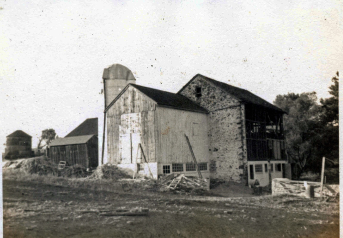 b & w photo of barn buildings and silo with work in progress