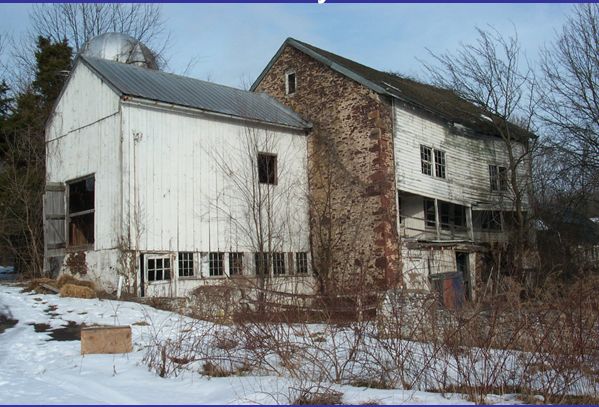 Color photo shows dilapidated farm buildings