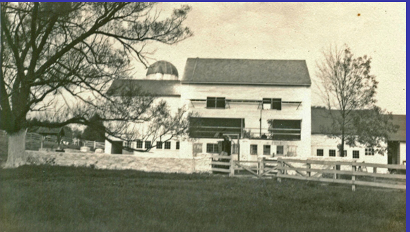 black and white photo shows work on the barn, now painted white