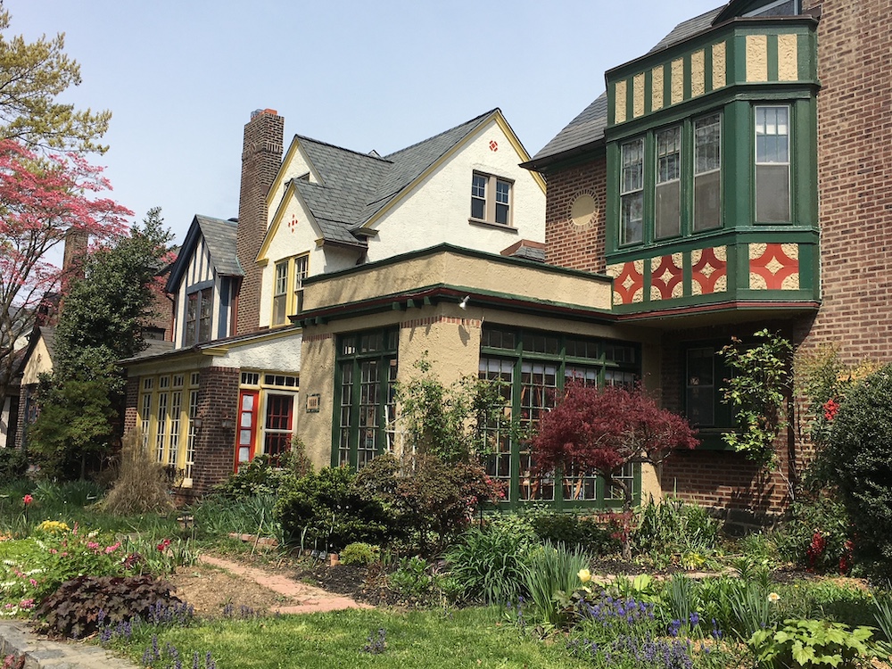 Row of homes feature artistic details, such as bay windows with decorative detailing and brick medallions set in stucco facades