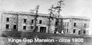 old black and white photo shows a big stone house with a flat roof