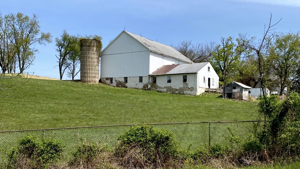 Hanby Farm nestled on a hillside with silo, white barn and other farm outbuildings