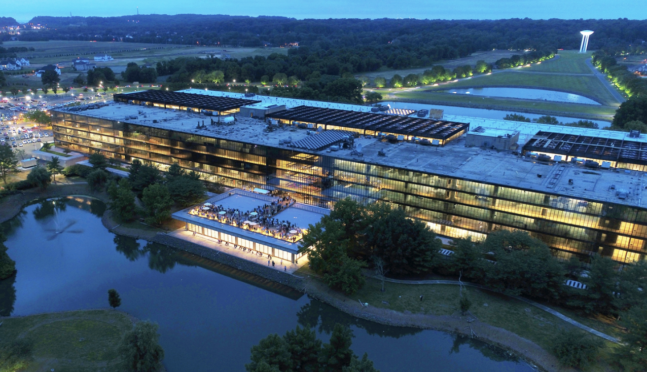 Aerial evening view of the completed Bell Works complex, with Saarinen's building and the iconic water tower lit up at dusk
