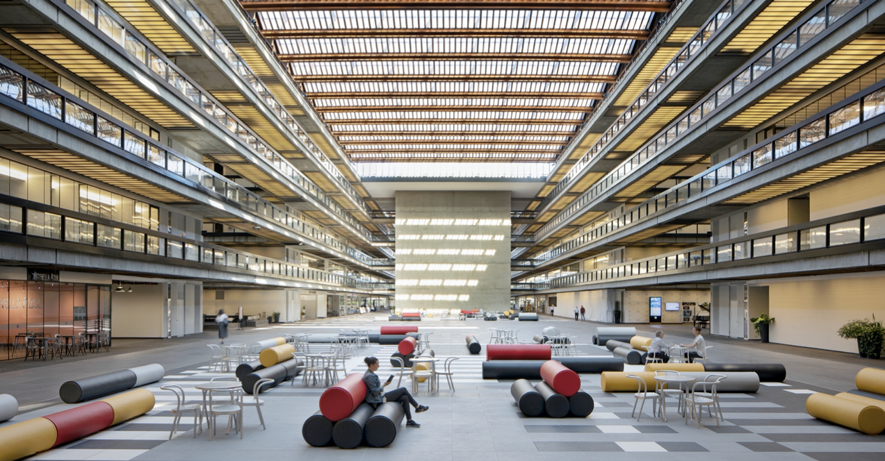 Bell Works atrium with glass ceiling, multi-level balconies, and open seating at ground level
