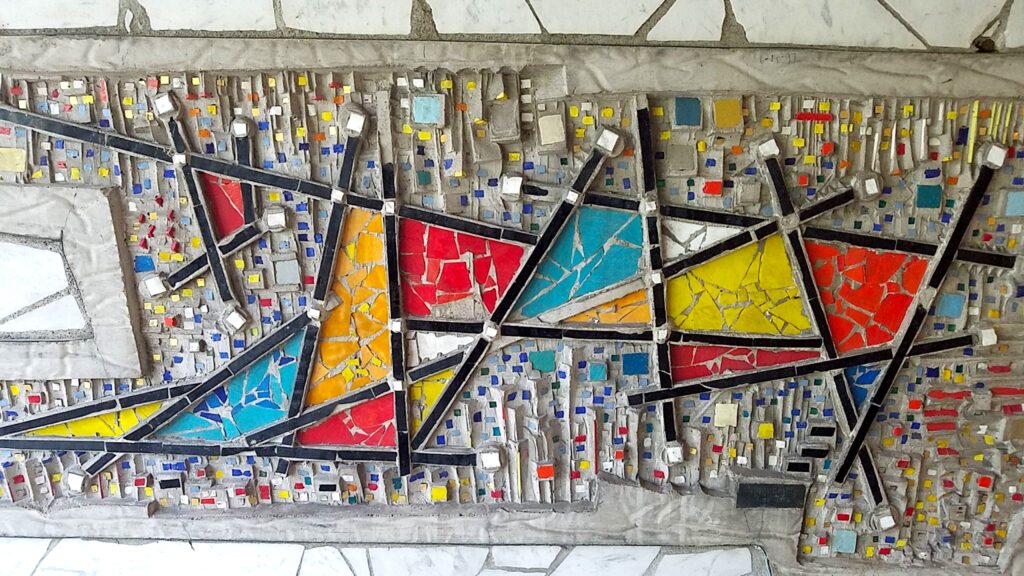 Abstract mosaic panel by Virgil Cantini with geometric shapes in red, orange, blue, and yellow